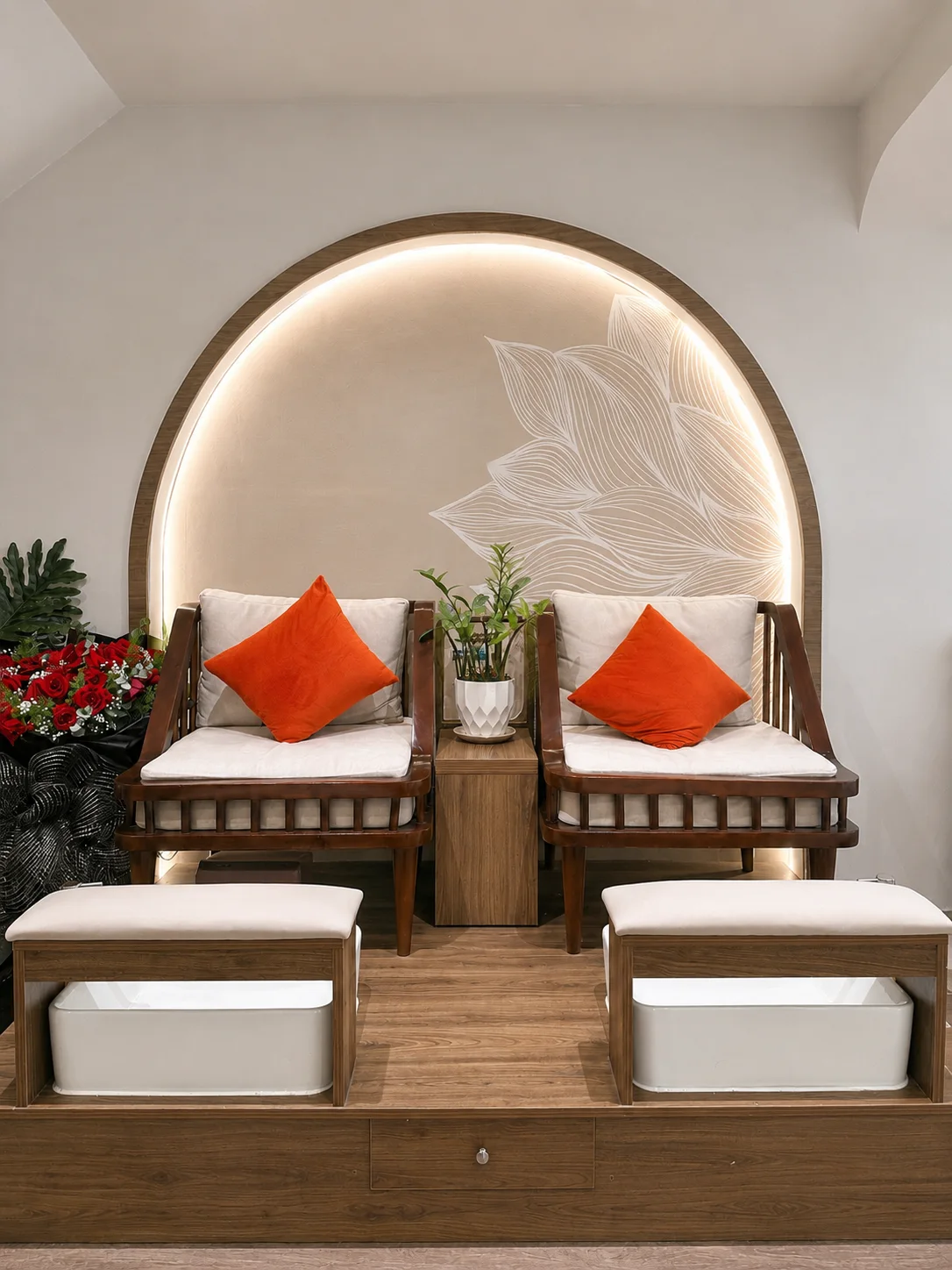 A pedicure lounge nook with rattan armchairs beneath lotus arch artwork